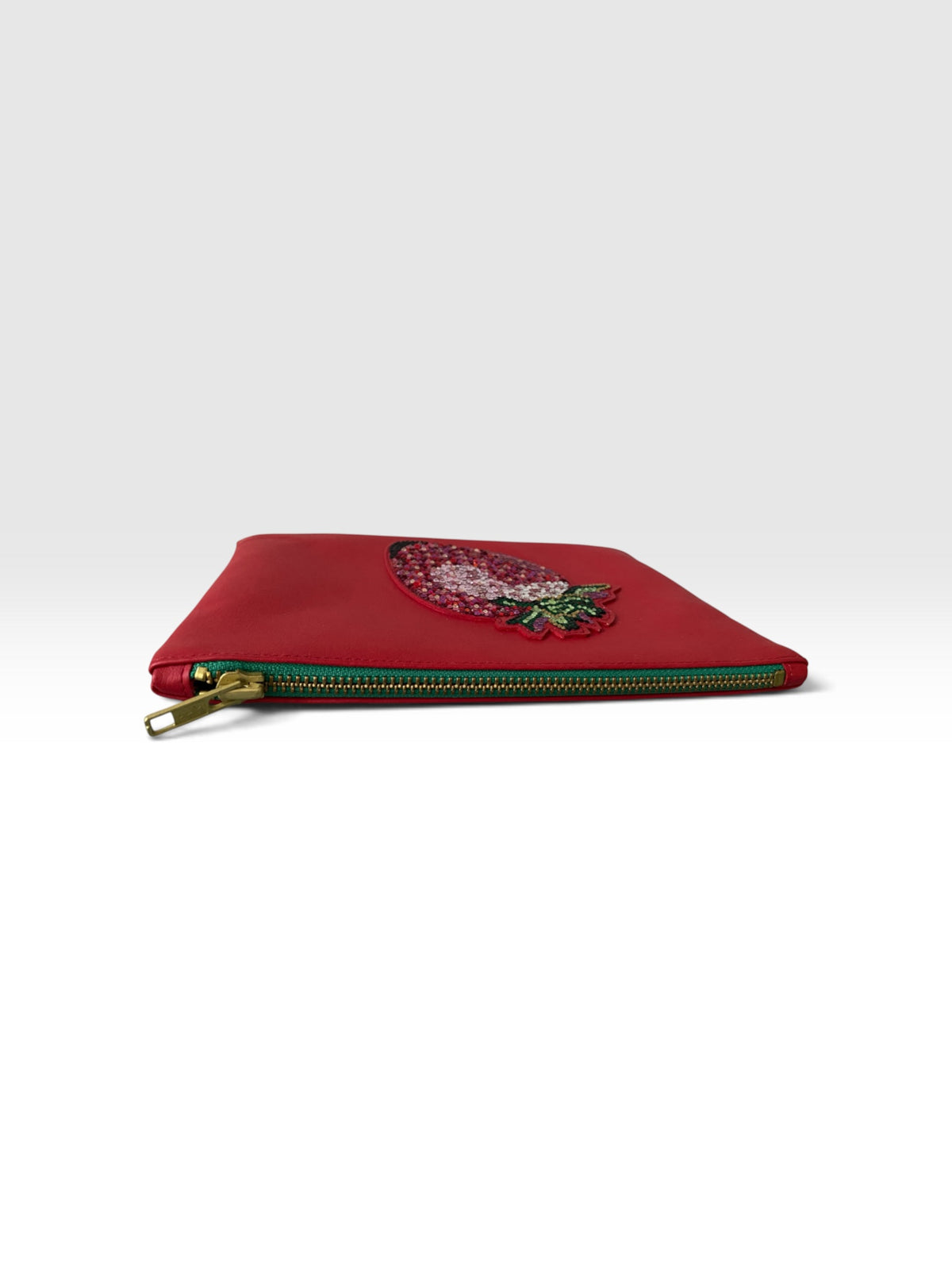 Liegende Strawberry Clutch mit sichtbarem Forest-Green-Reißverschluss und Darstellung ihrer ungefähren Größe
