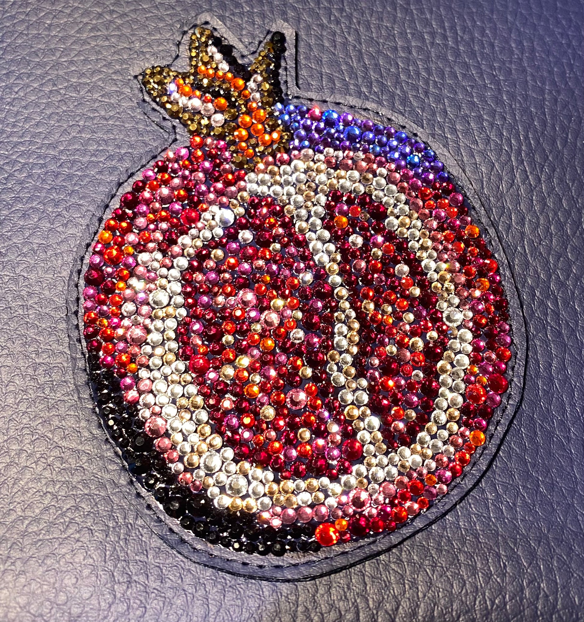 Detailaufnahme der Glas-Strasssteine der Pomegranate Clutch in Rot- und Rosetönen, Champagner und Schwarz

