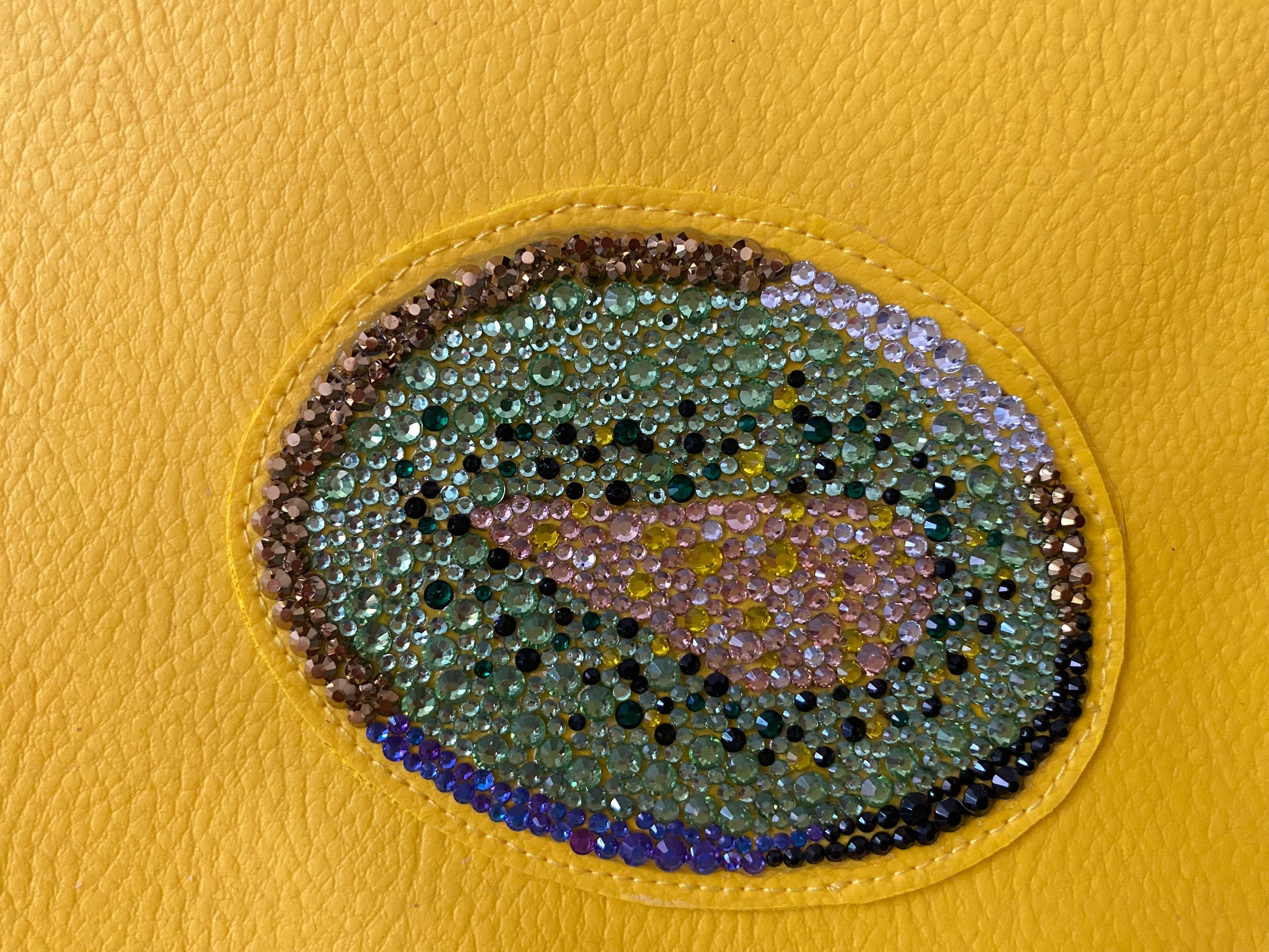 Detailaufnahme der Glas-Strasssteine der Kiwi Clutch in Grün- und Goldtönen, Champagner und Schwarz
